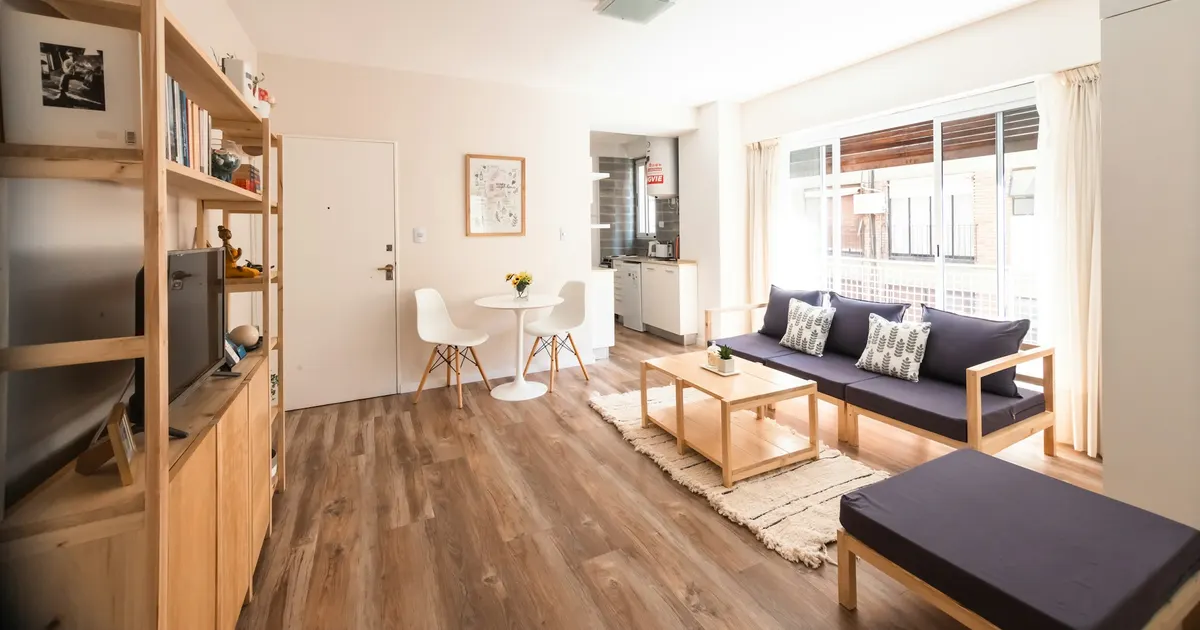 Bright living room with a light plank floor running toward a wall of windows